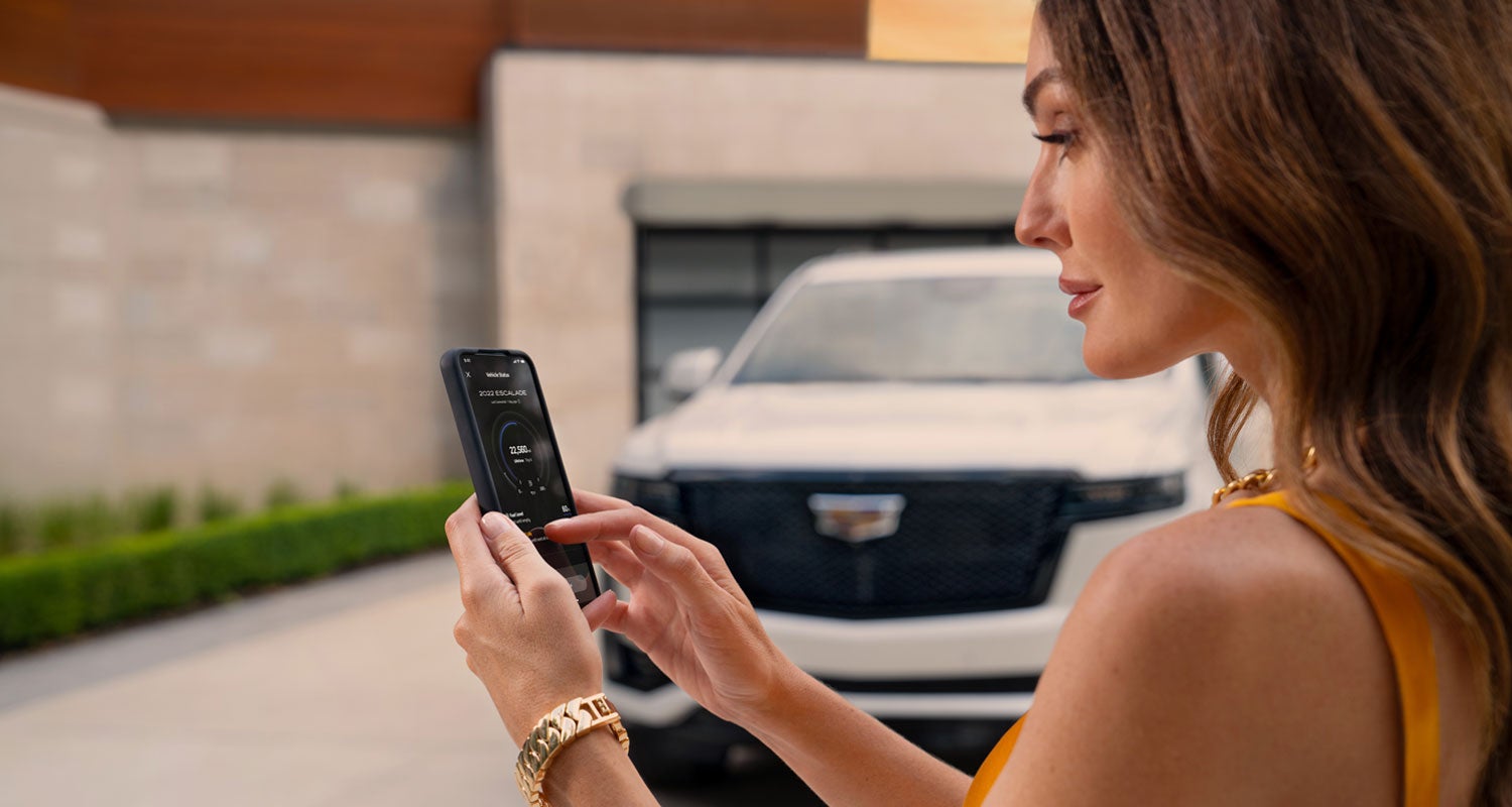 lady checking her mobile with a Cadillac vehicle background | Flow Cadillac of Wilmington in Wilmington NC